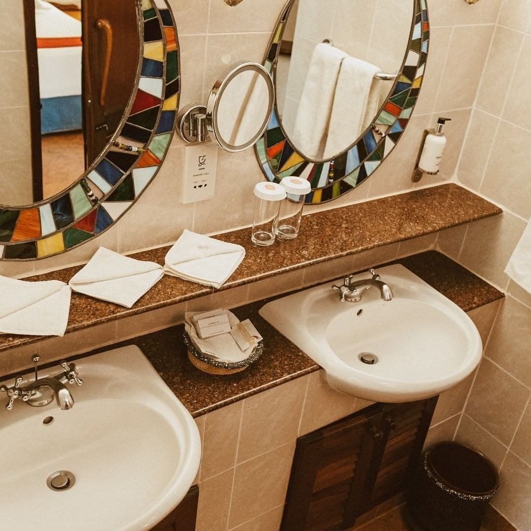 Bathroom at Amboseli Serena Safari Lodge with twin basins under oval mirrors framed in colourful mosaic
