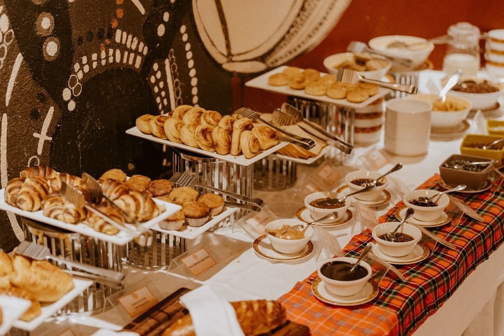 Breakfast buffet at Amboseli Serena Safari Lodge with pastries, croissants and preserves laid on red checked cloths