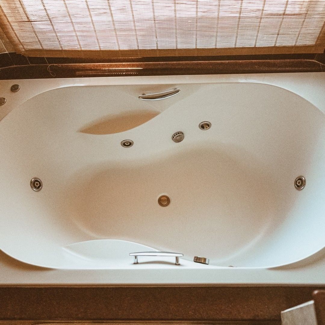 Deep white jacuzzi bath with jets set into a tiled surround under a skylight at Amboseli Serena Safari Lodge