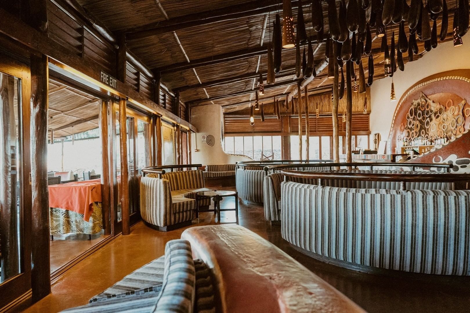 Restaurant at Amboseli Serena Safari Lodge with striped banquettes, a timber ceiling and wide windows onto the garden