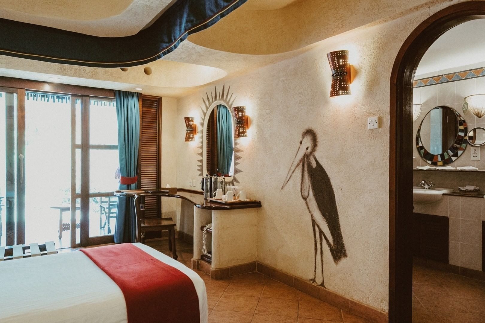 Room at Amboseli Serena Safari Lodge with a stork painted on the wall beside an arched doorway and round mirrors