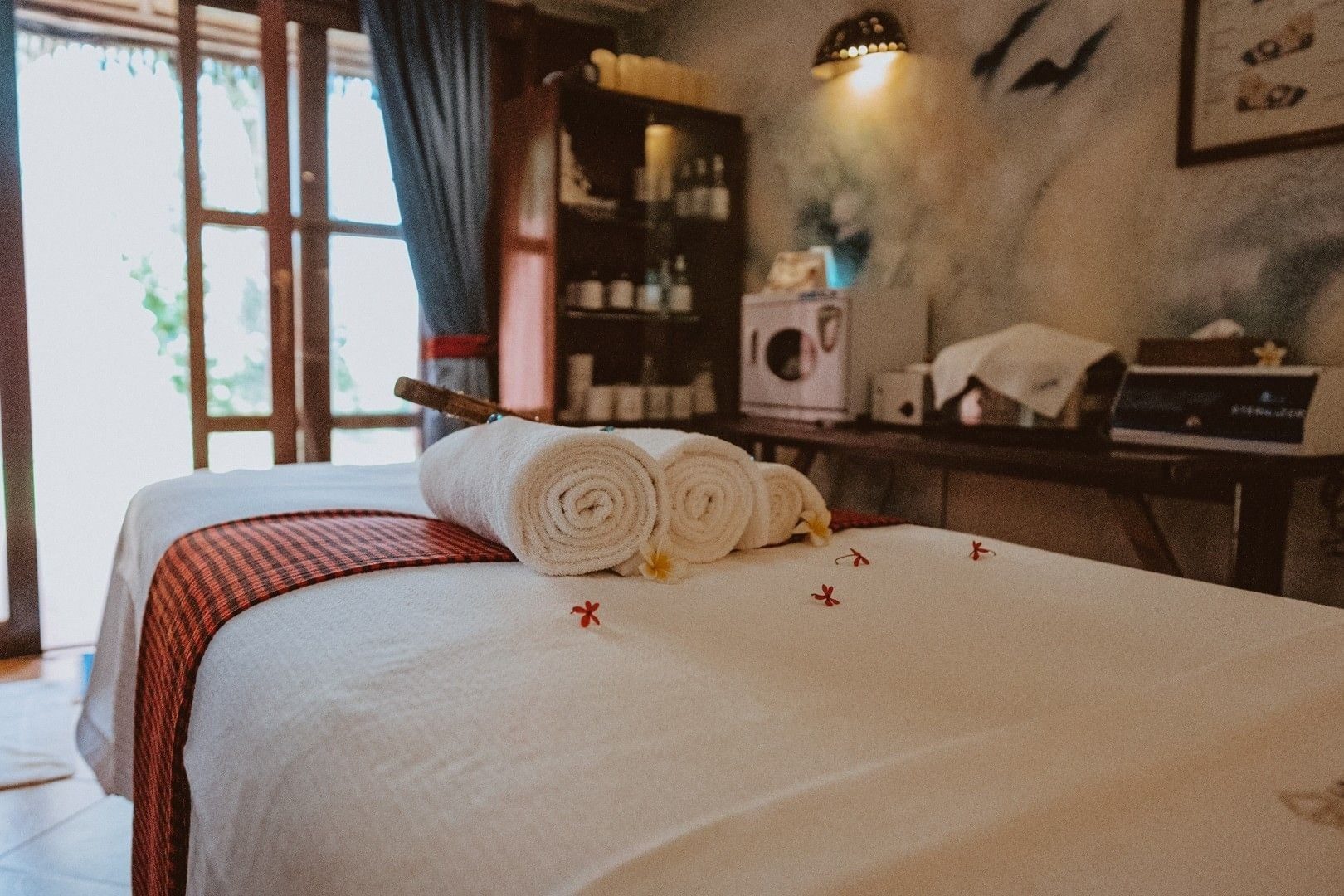 Spa treatment room at Amboseli Serena Safari Lodge with a massage bed, rolled towels and a carved wooden cabinet