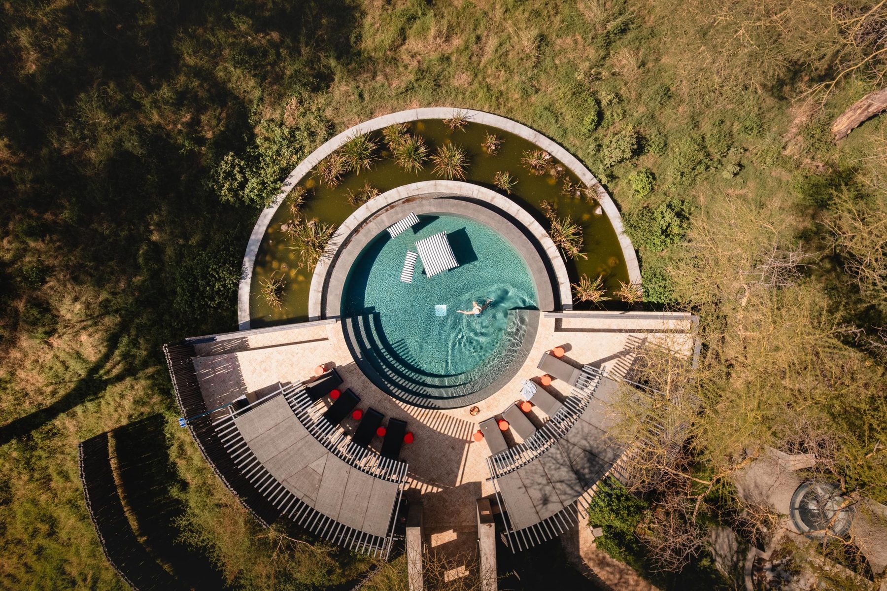 Aerial view of a circular building with a round pool surrounded by trees at Angama Amboseli
