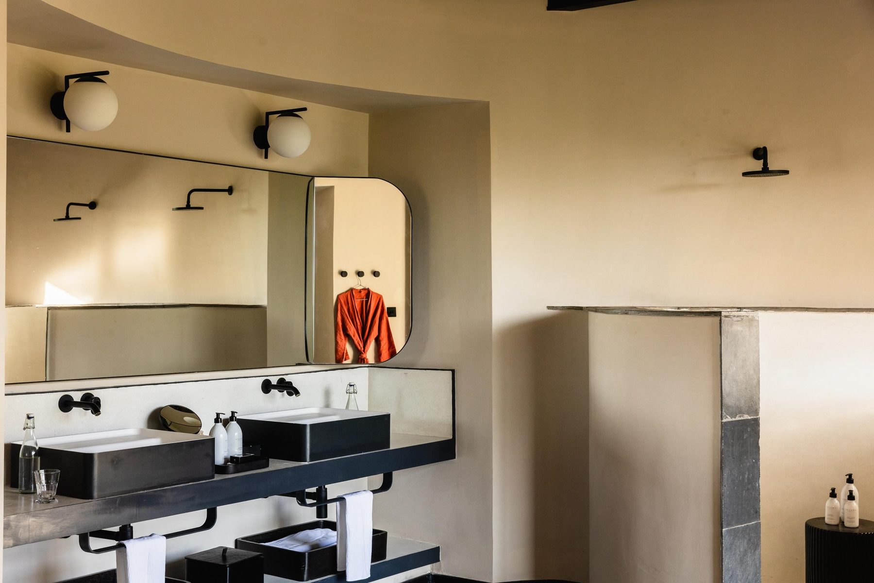Twin basins and a curved mirror on a stone vanity in a suite bathroom at Angama Amboseli