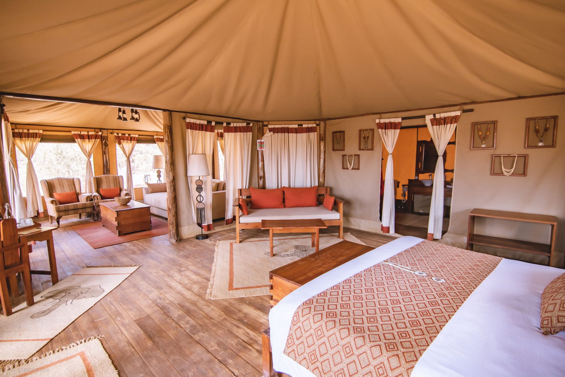 Spacious tent at Elephant Bedroom Camp with a double bed, wooden floors and a sofa under the canvas roof