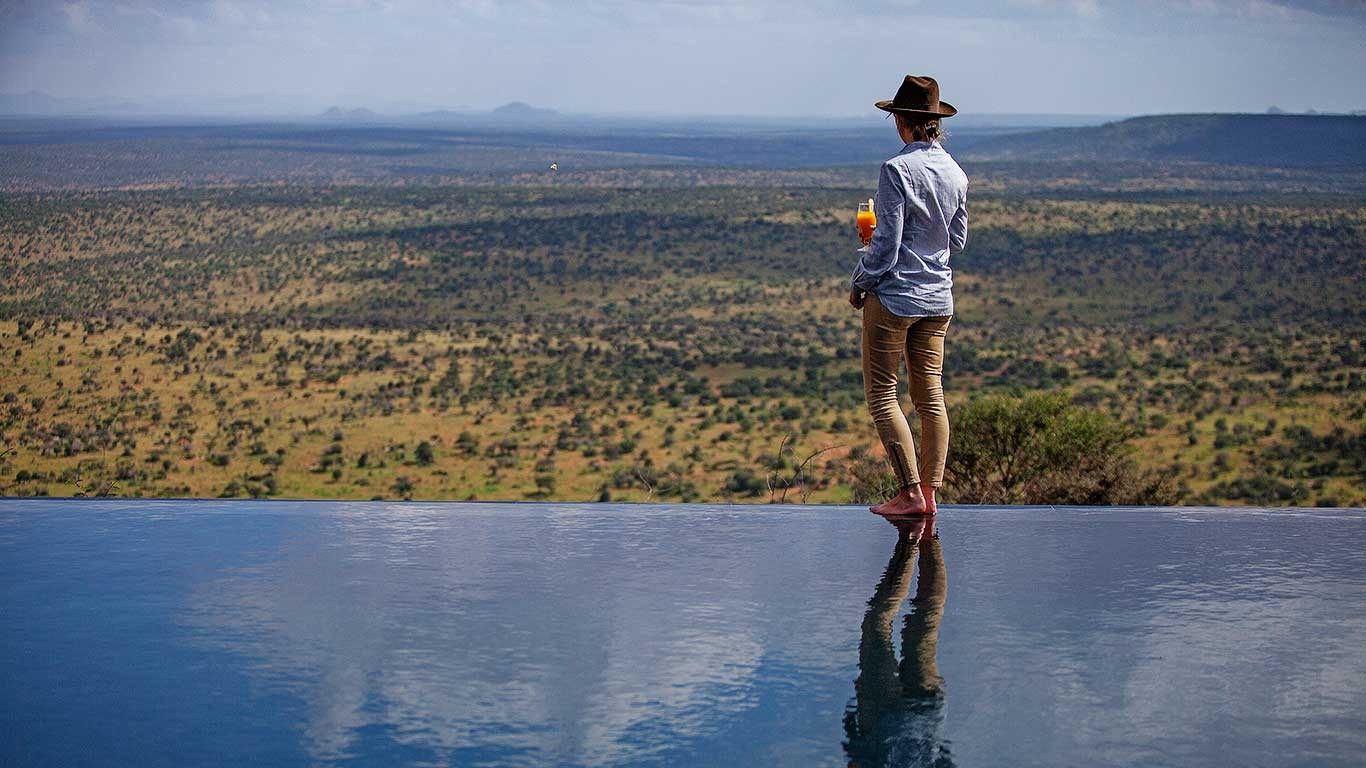 Guest standing at the edge of the infinity pool at Elewana Loisaba Tented Camp, above wide bush-covered plains