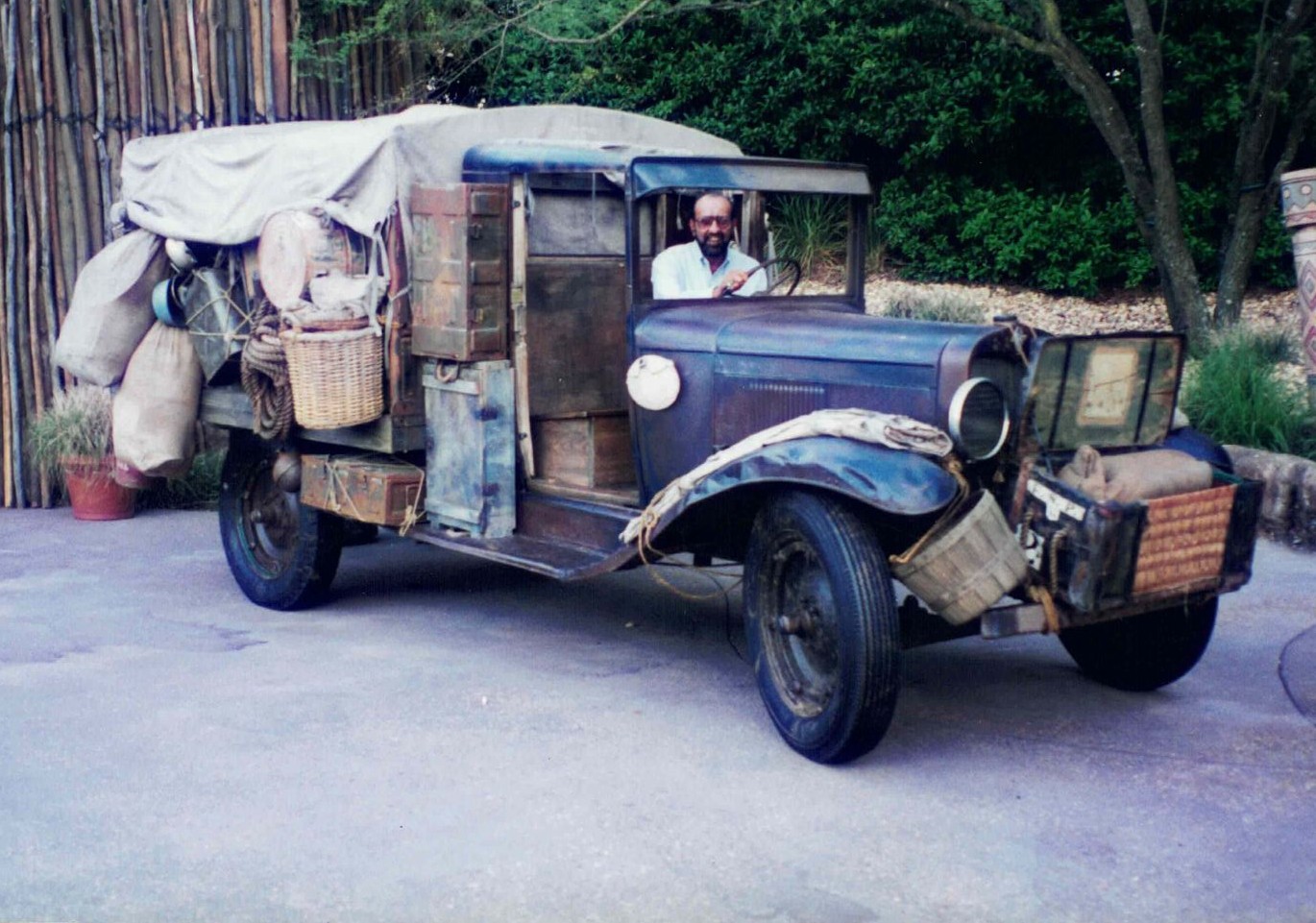 Feeroz Jagani at the wheel of a vintage truck loaded with baskets, sacks and trunks, 1994