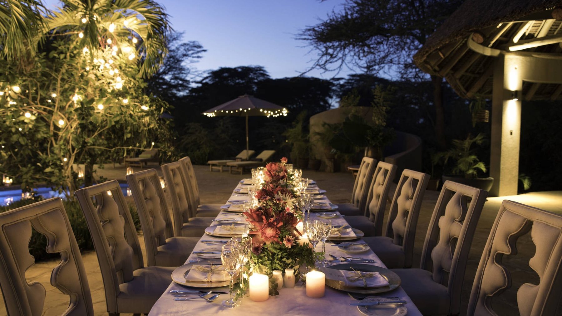 Long candlelit dinner table with flowers under fairy lights at Finch Hattons in the evening