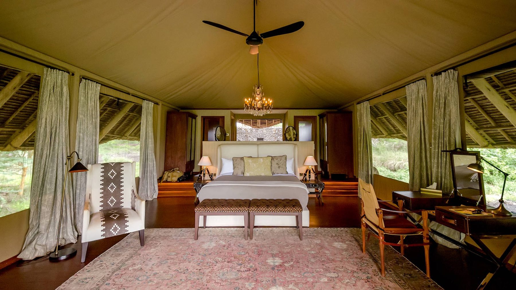 Tented suite at Finch Hattons with a large bed, a chandelier, a ceiling fan and a patterned rug