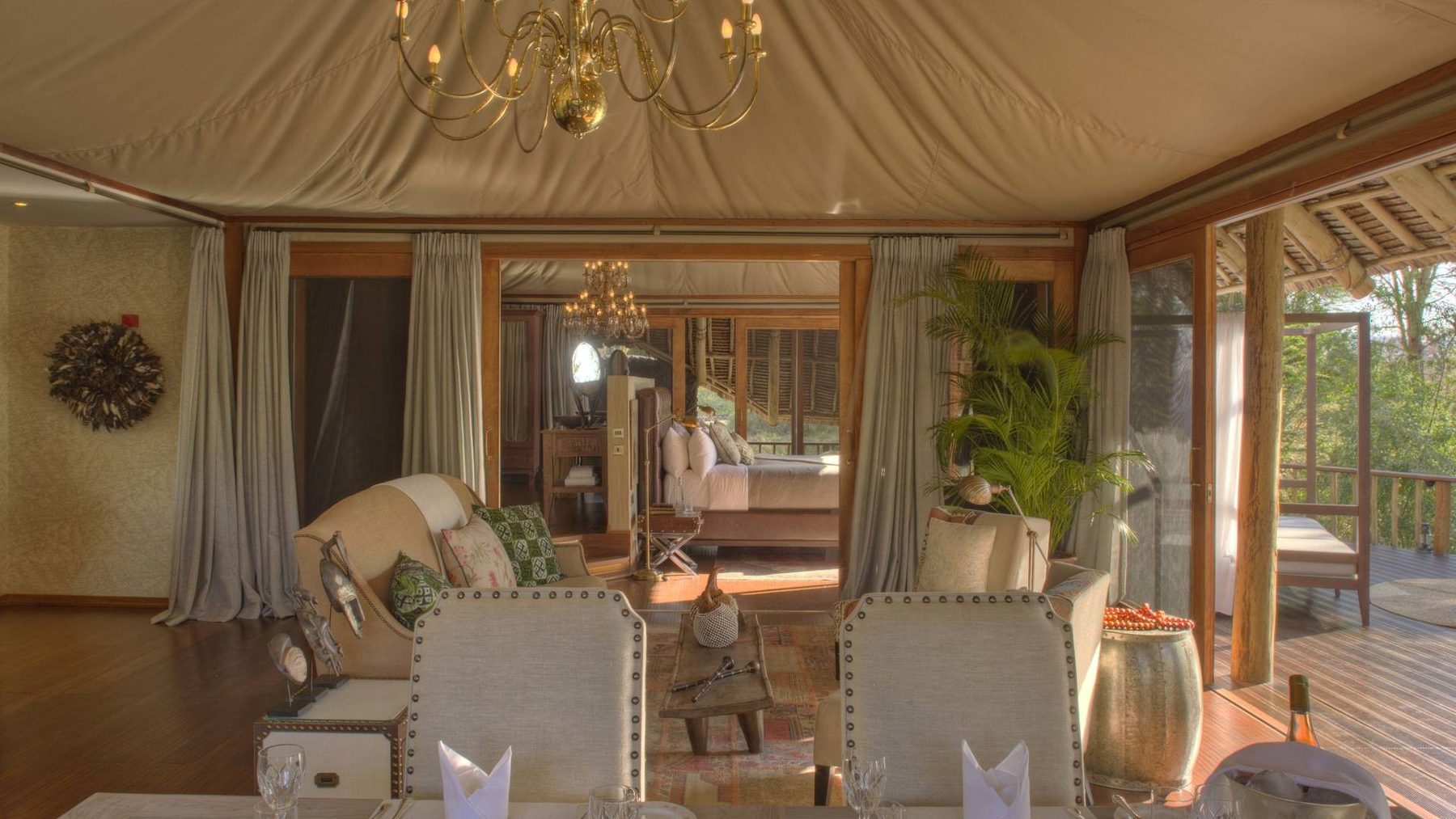 Sitting area with armchairs and a chandelier inside a large tented suite at Finch Hattons