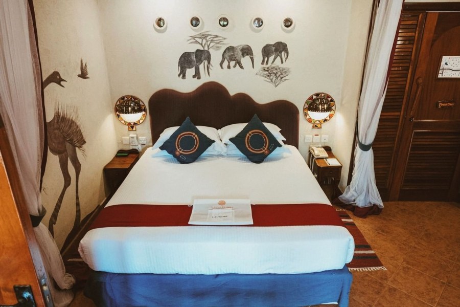 Bedroom at Amboseli Serena Safari Lodge with a double bed and elephants painted on the wall above