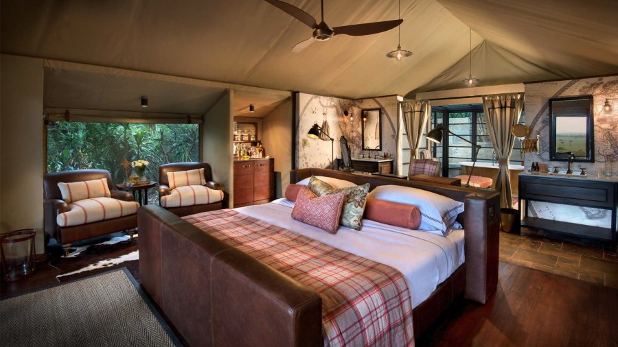 Tented suite at &Beyond Bateleur Camp with a leather-framed bed, two armchairs and a bathtub behind