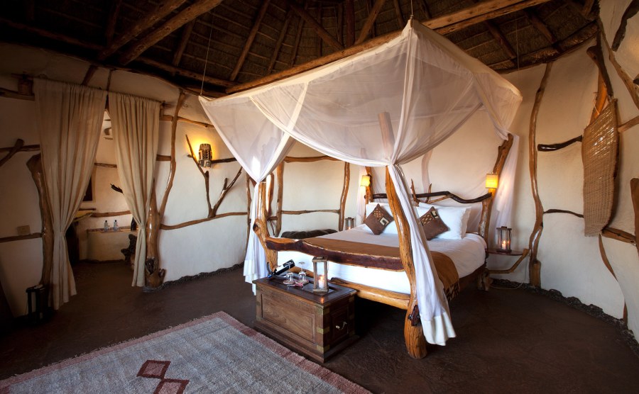 Room at Satao Elerai with a four-poster bed of rough branches, mosquito netting and a thatched roof