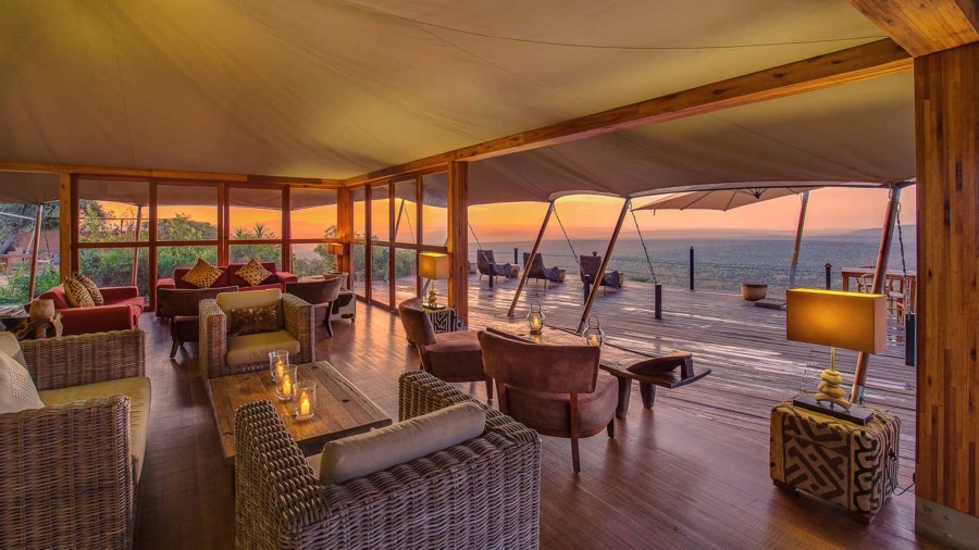 Lounge tent at Elewana Loisaba Tented Camp with wicker sofas and a deck looking out at sunset