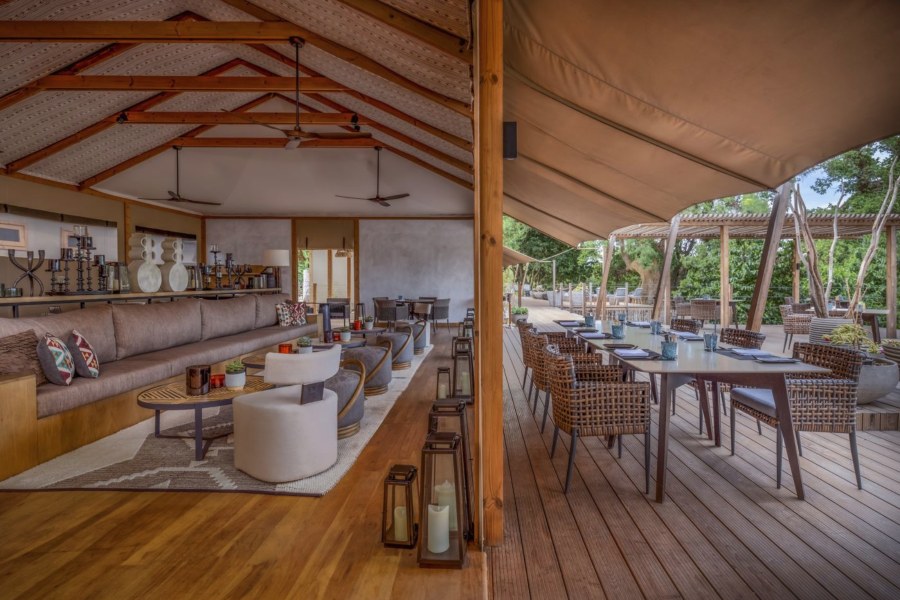 Lounge and deck at JW Marriott Masai Mara Lodge with long sofas, lanterns and a dining table outside