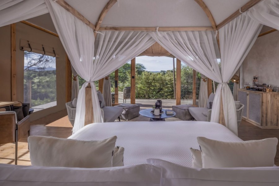 Tented suite at JW Marriott Masai Mara Lodge with a four-poster bed facing a deck and trees
