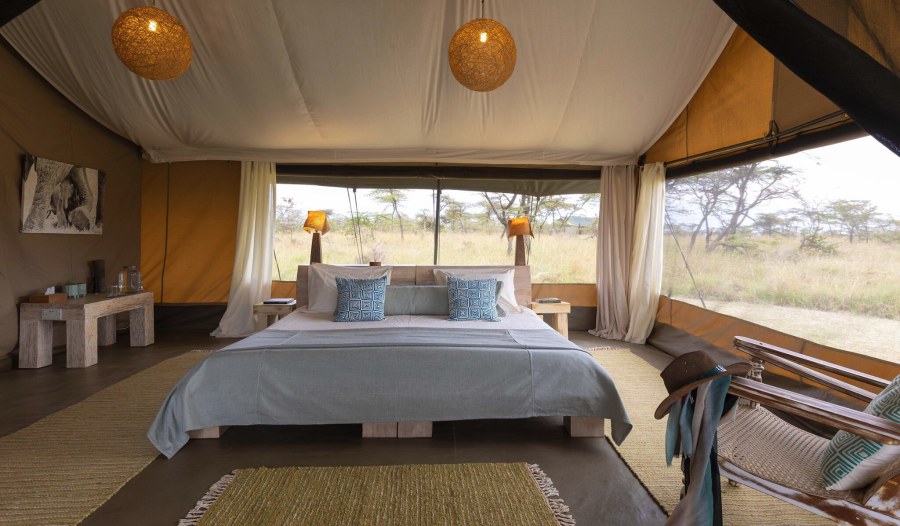 Tent at Kicheche Bush Olare with a large bed facing open sides that look out onto grassland and acacia trees