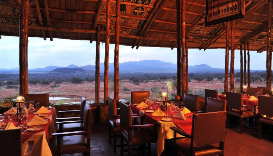 Open-sided dining room at Kilaguni Serena Safari Lodge looking over a waterhole and hills in Tsavo West at dusk