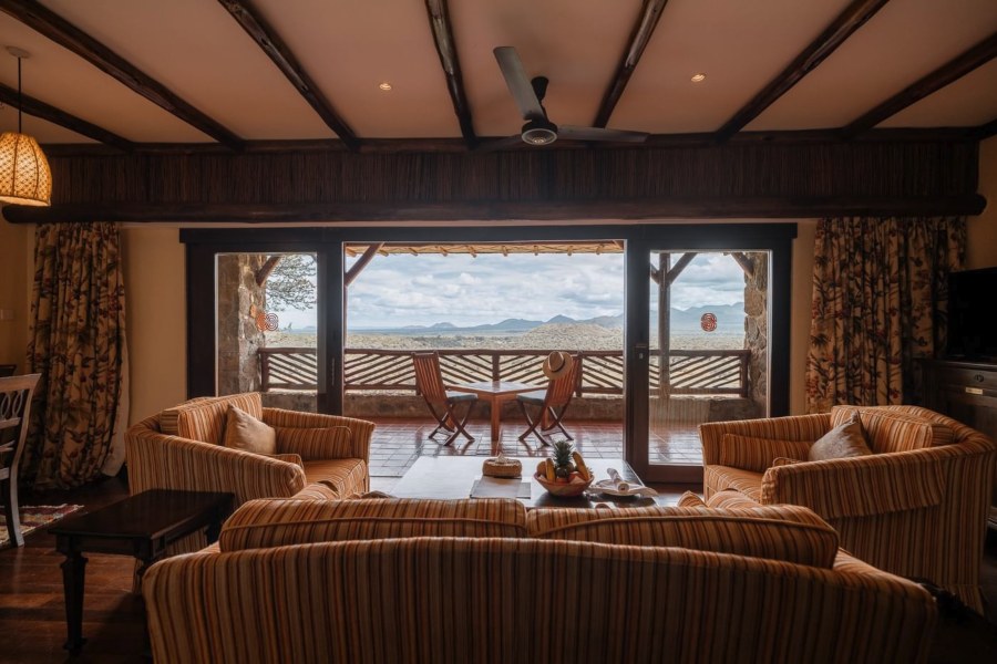 Sitting room with striped sofas at Kilaguni Serena Safari Lodge, opening onto a balcony with views over Tsavo West
