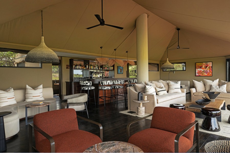 Tented lounge and bar at Mahali Mzuri with cream sofas, rust-coloured armchairs and woven pendant lights
