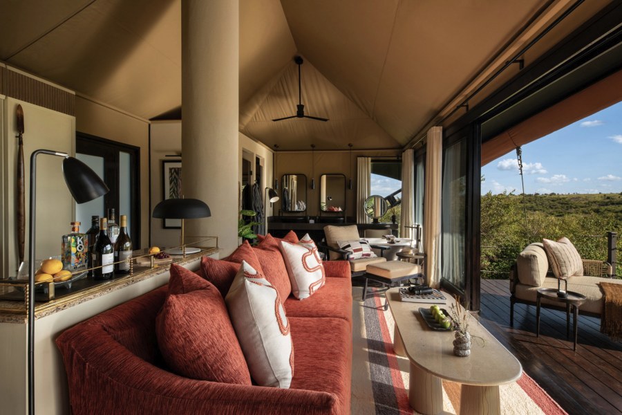 Tented suite sitting area at Mahali Mzuri with a red sofa, opening onto a deck that looks over green bush