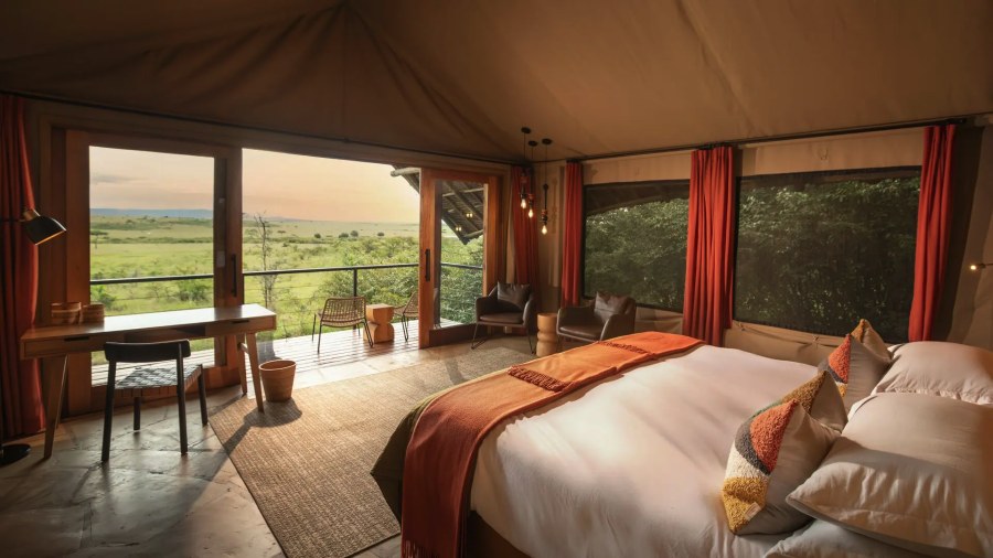 Tent at Naboisho Camp with a large bed and glass doors to a deck looking over open grassland