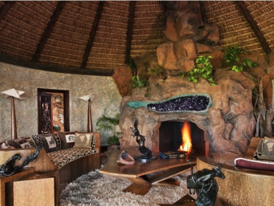 Round thatched sitting room at Ol Jogi with a rock fireplace set with a band of purple stone, and a curved sofa