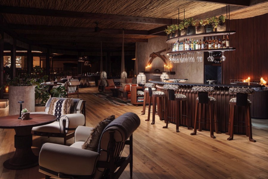 Candlelit bar and lounge at The Ritz-Carlton, Masai Mara Safari Camp, with patterned bar stools and armchairs