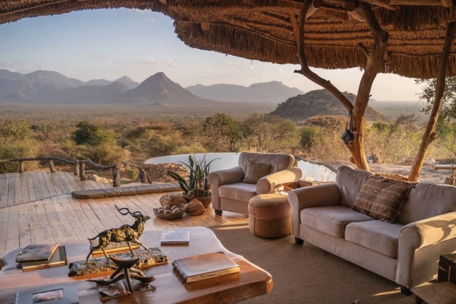Sofas on a thatched deck beside a pool, looking out to mountains at Sarara Camp