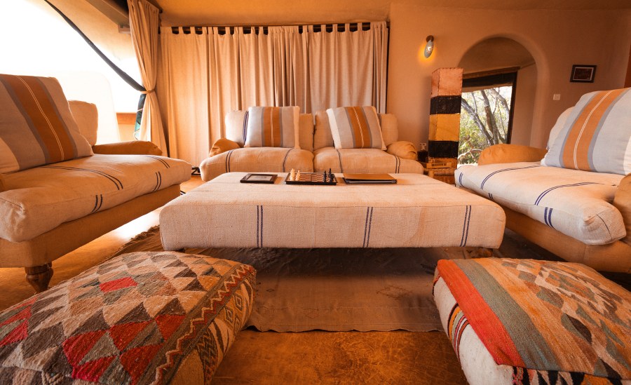 Striped sofas and patterned floor cushions around a low table with a chess board at Saruni Samburu