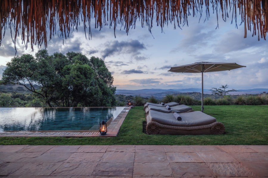 Pool and loungers on a lawn looking over wooded hills at dusk at Sirai House