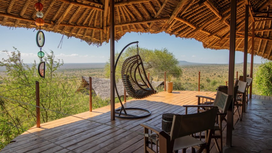 Hanging wicker chair and safari chairs on a thatched deck over bushland at Soroi Cheetah Tented Camp