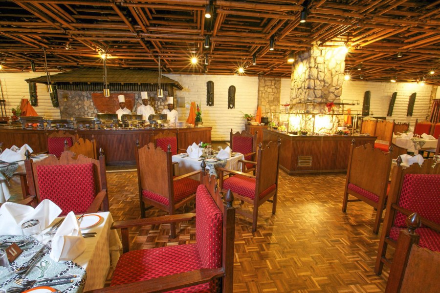Dining room with red upholstered chairs and chefs at a buffet counter at Taita Hills Safari Resort & Spa