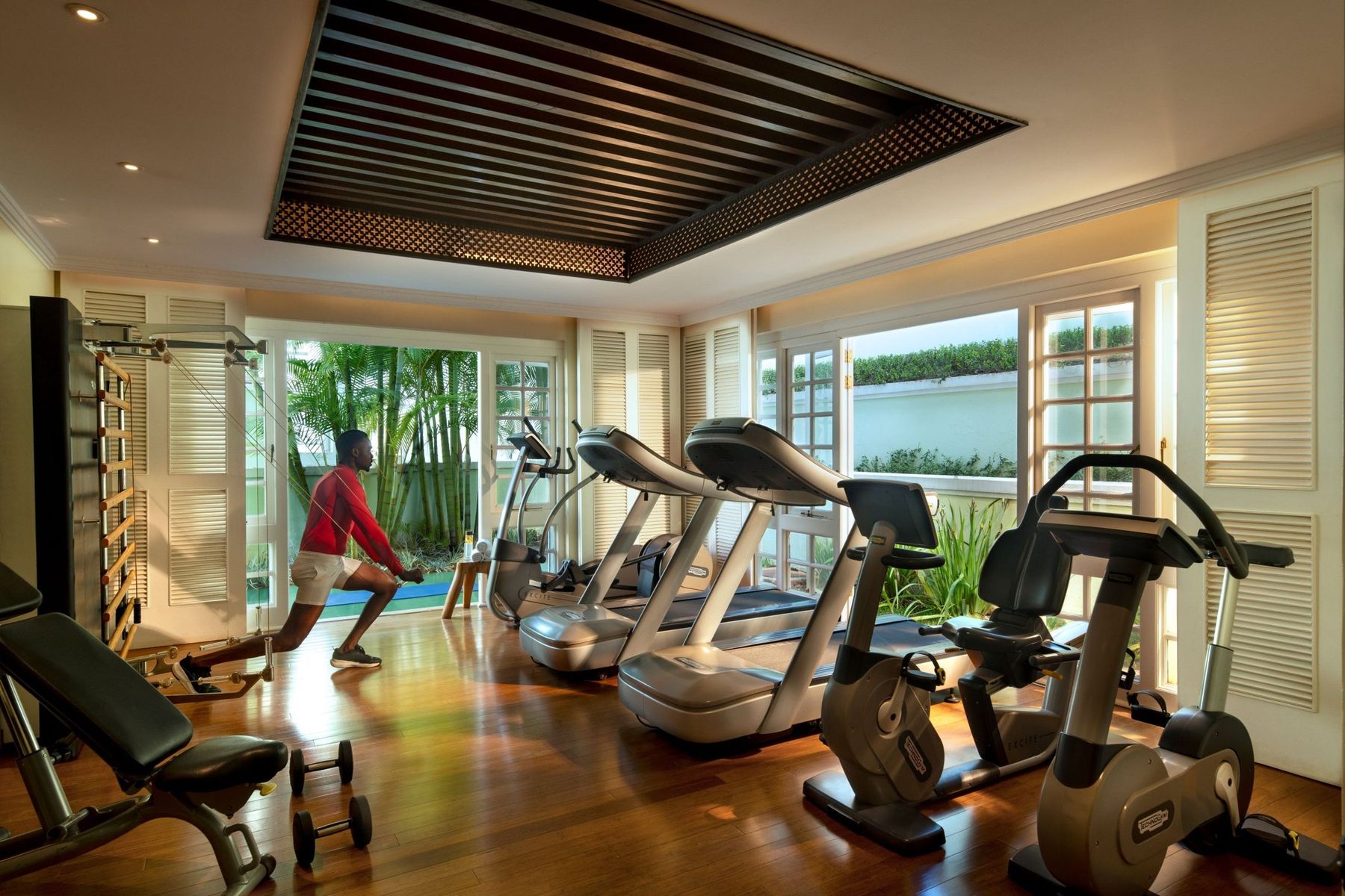 The gym at Hemingways Nairobi, with treadmills and bikes facing windows onto the garden