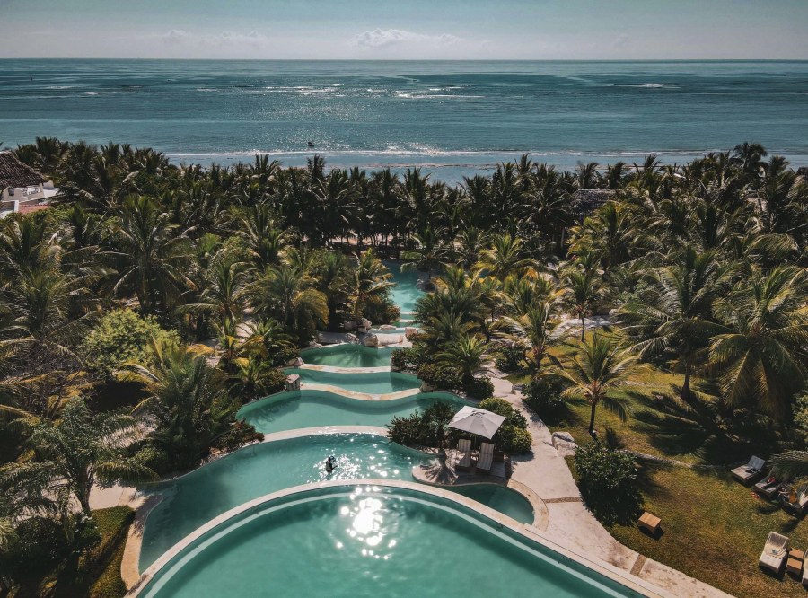 Aerial view of tiered pools among palm trees leading to the Indian Ocean at Swahili Beach Resort, Diani