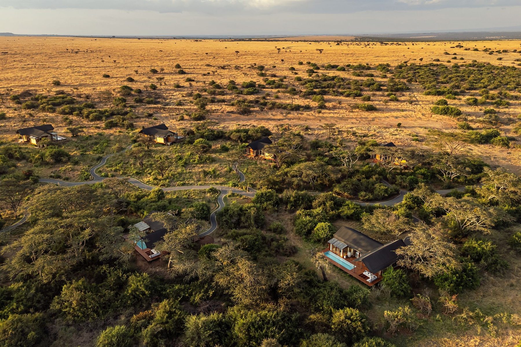 Aerial view of tented suites scattered through bush and grassland at JW Marriott Mount Kenya Rhino Reserve Safari Camp