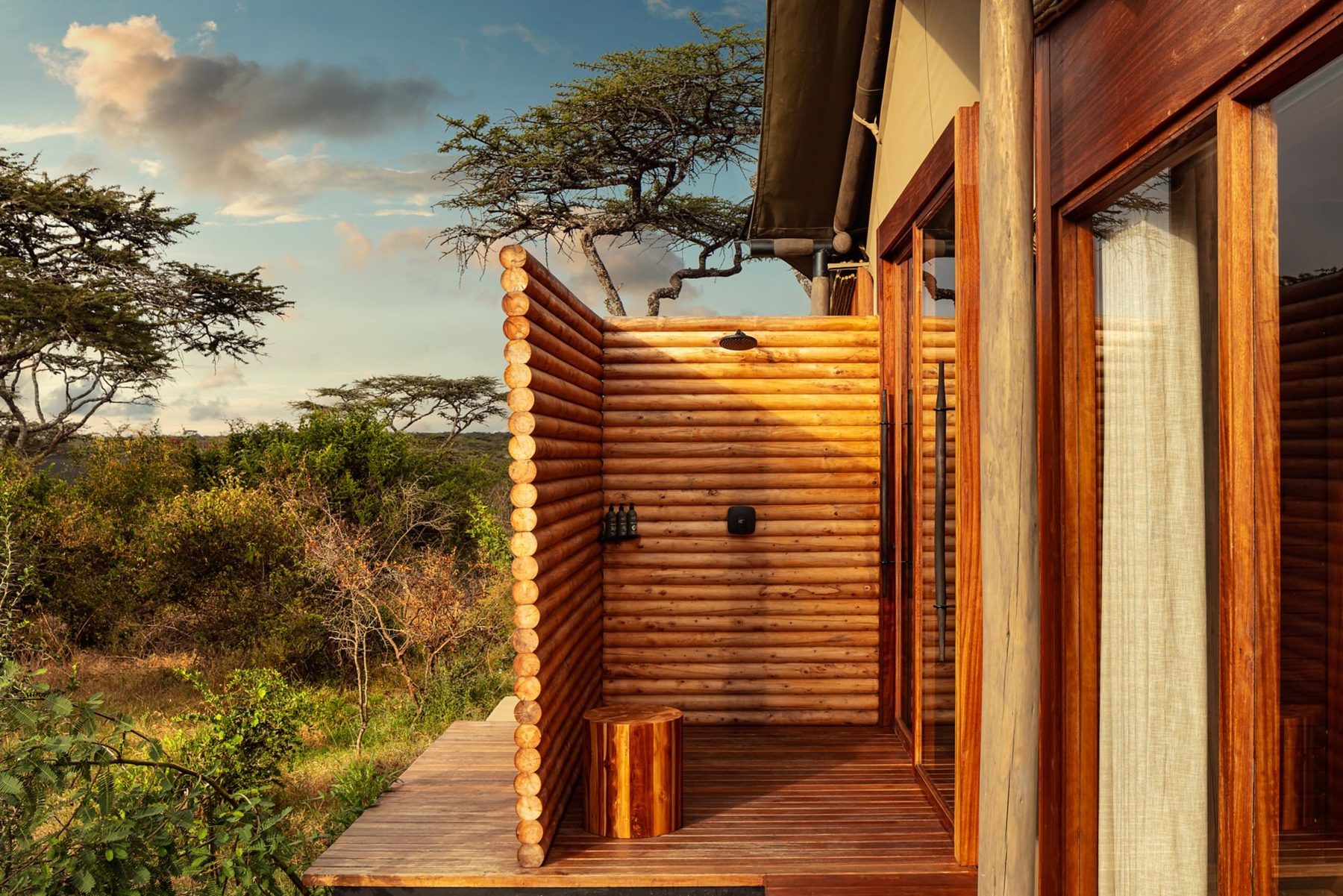 Timber-slatted outdoor shower on a suite deck at JW Marriott Mount Kenya Rhino Reserve Safari Camp, overlooking the bush