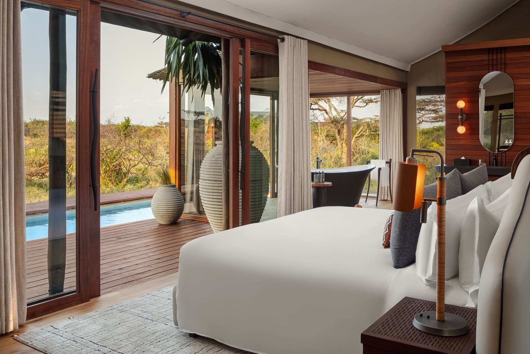 Tented suite at JW Marriott Mount Kenya Rhino Reserve Safari Camp with a white bed facing glass doors and a plunge pool