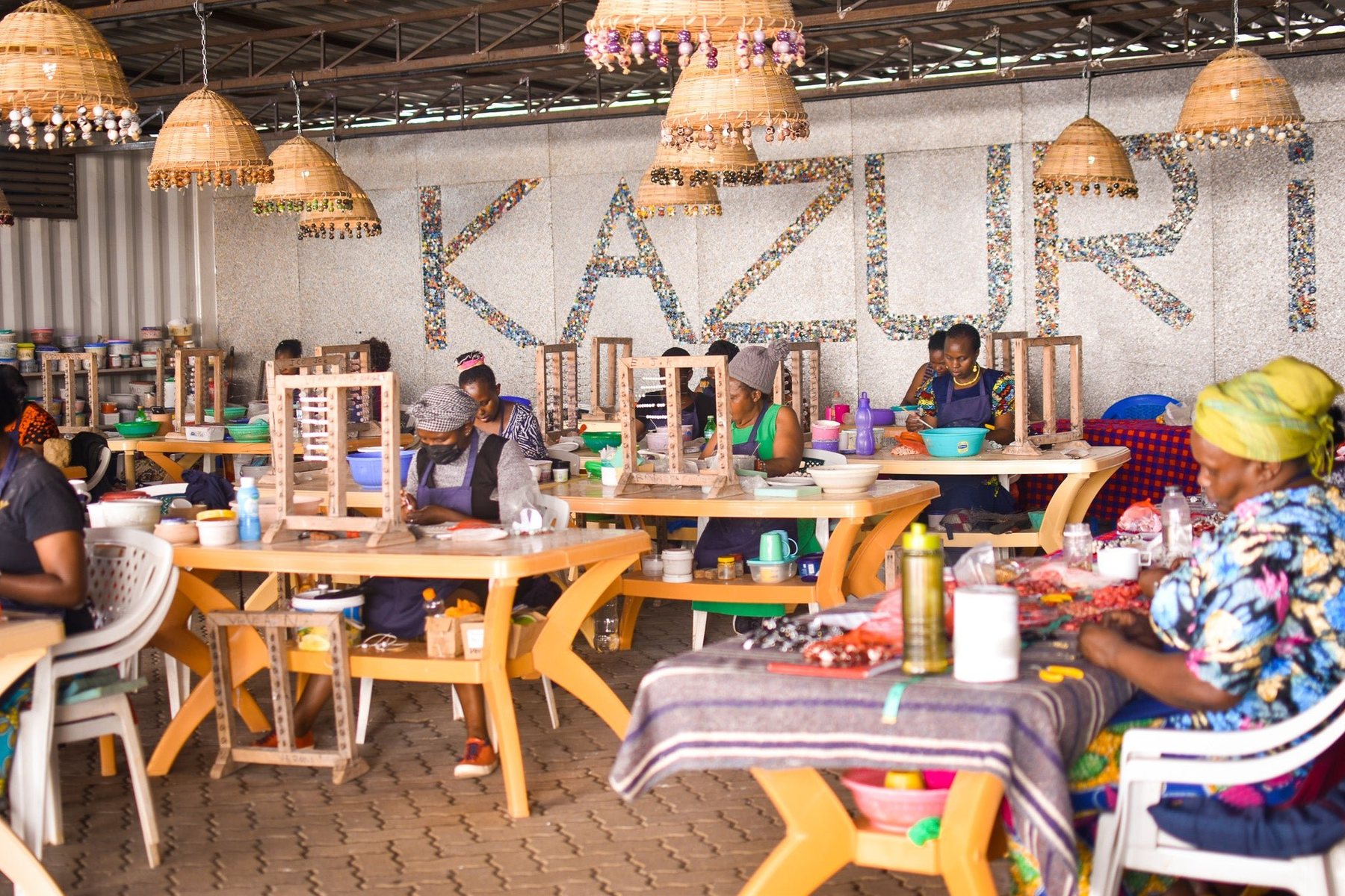 Women shaping and painting ceramic beads at long tables in the Kazuri workshop in Karen