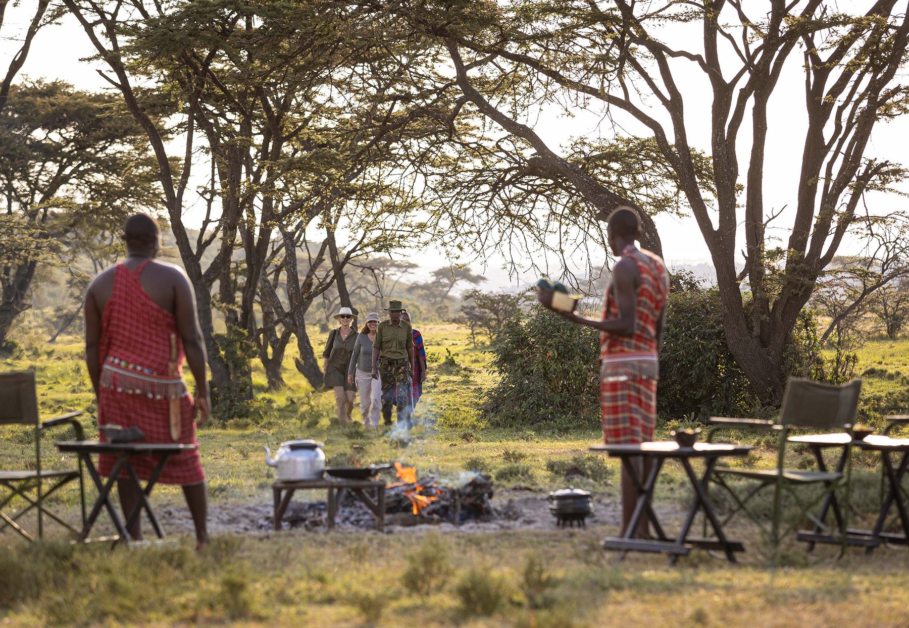 Maasai guides preparing a bush breakfast over a fire under acacia trees for guests of Kicheche Bush Olare