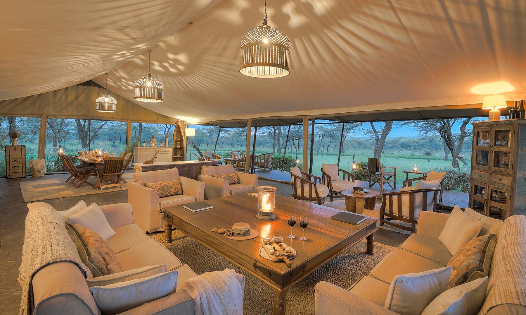 Main lounge tent at Kicheche Bush Olare with cream sofas around a candlelit coffee table and hanging lanterns