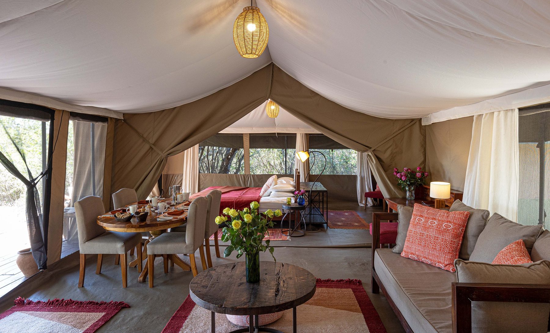 Sitting and dining area inside a large tent at Kicheche Mara North with sofas, a table and fresh flowers