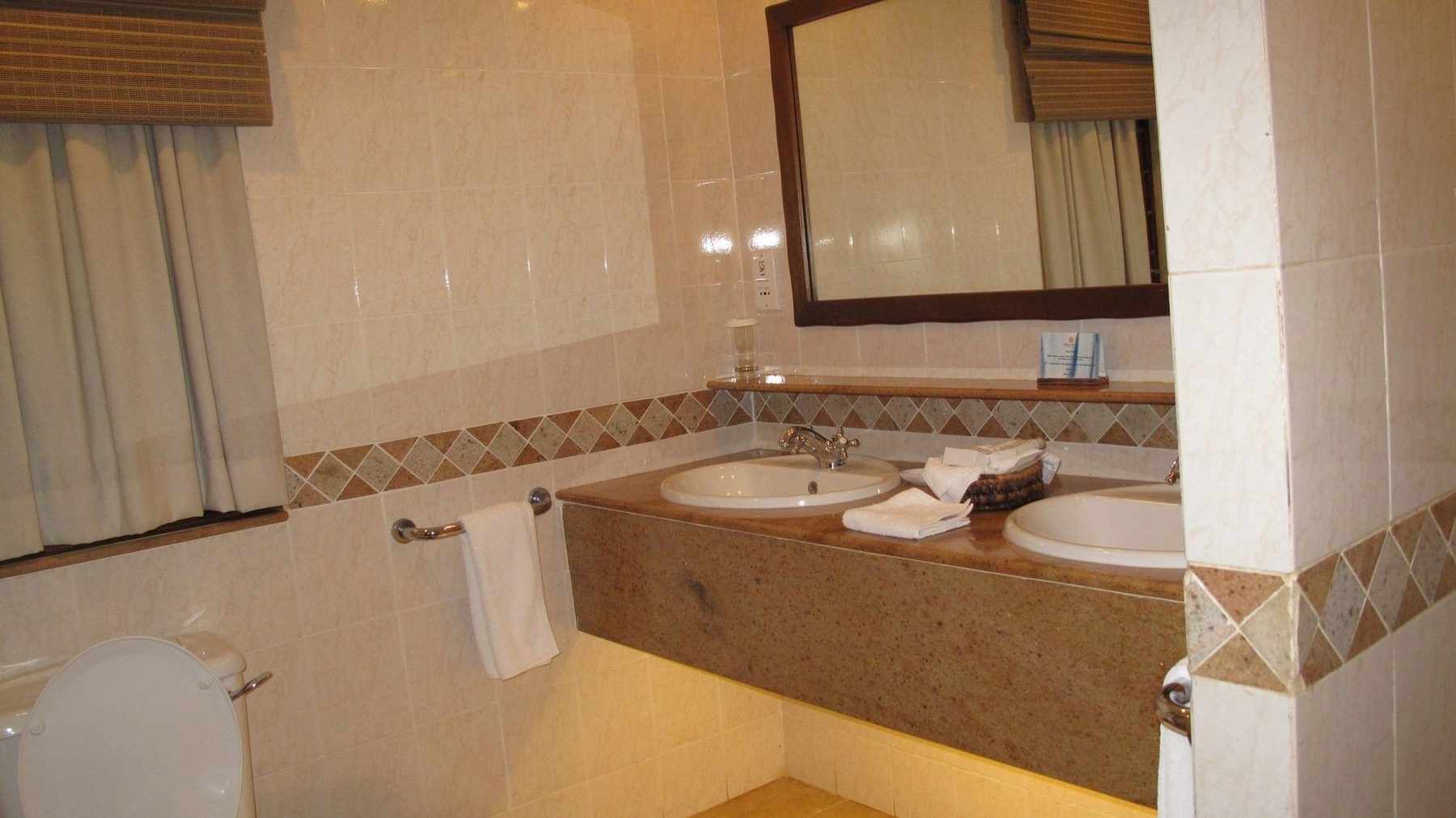 Bathroom at Kilaguni Serena Safari Lodge with twin basins set in a marble counter beneath a long mirror