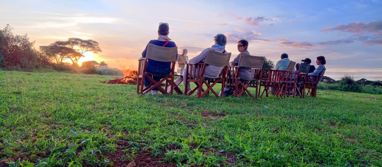 Guests in safari chairs watching the sunset over the plains on a sundowner near Kilima Safari Camp
