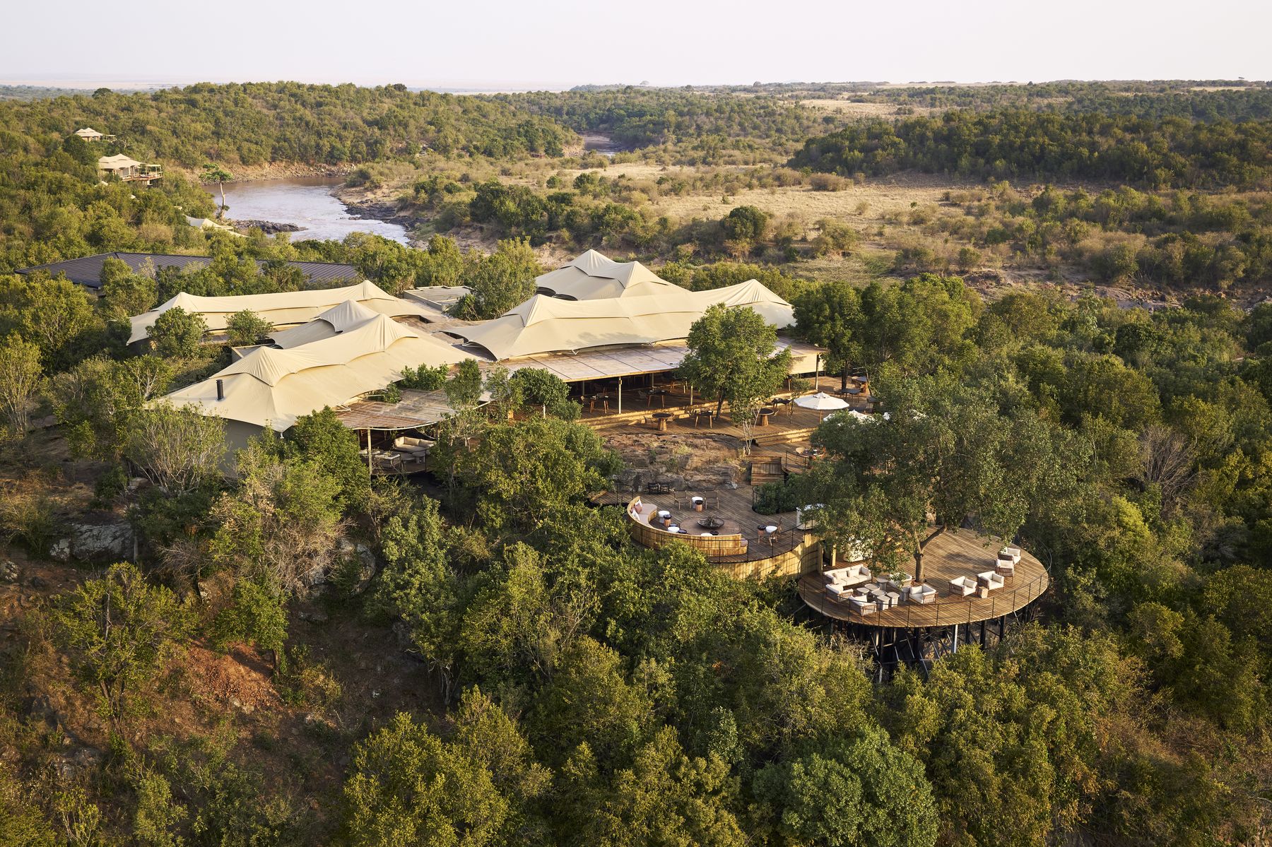 Aerial view of Kinara’s main areas and a round dining deck among trees near the Mara River