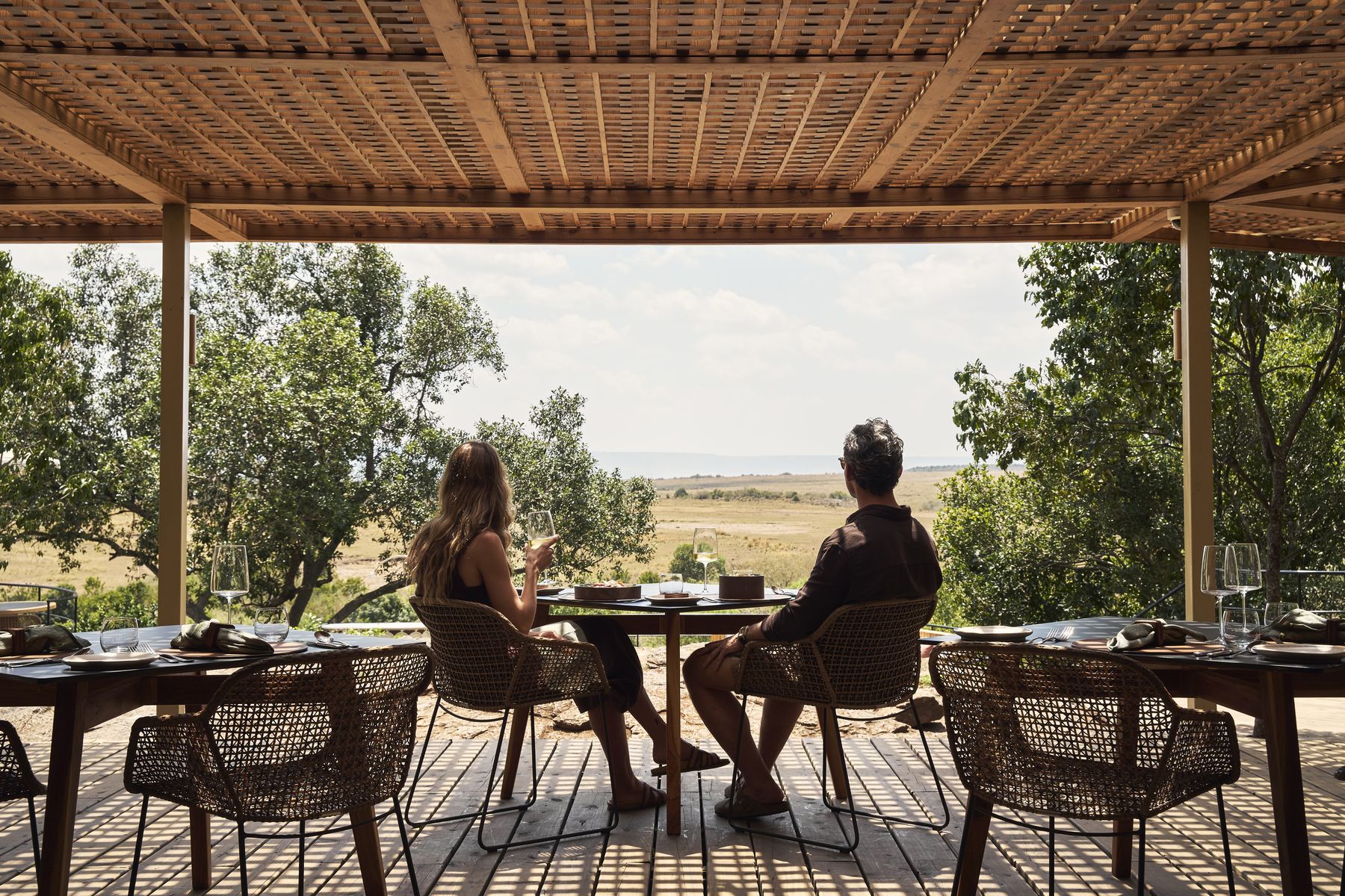Two guests at lunch on a shaded terrace at Kinara looking out over the plains