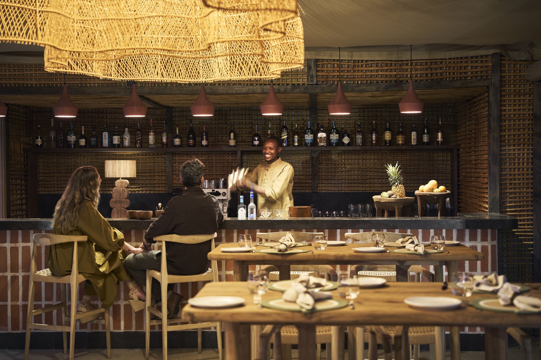 Guests seated at the bar at Kinara in the evening, with a barman behind the counter and warm pendant lights