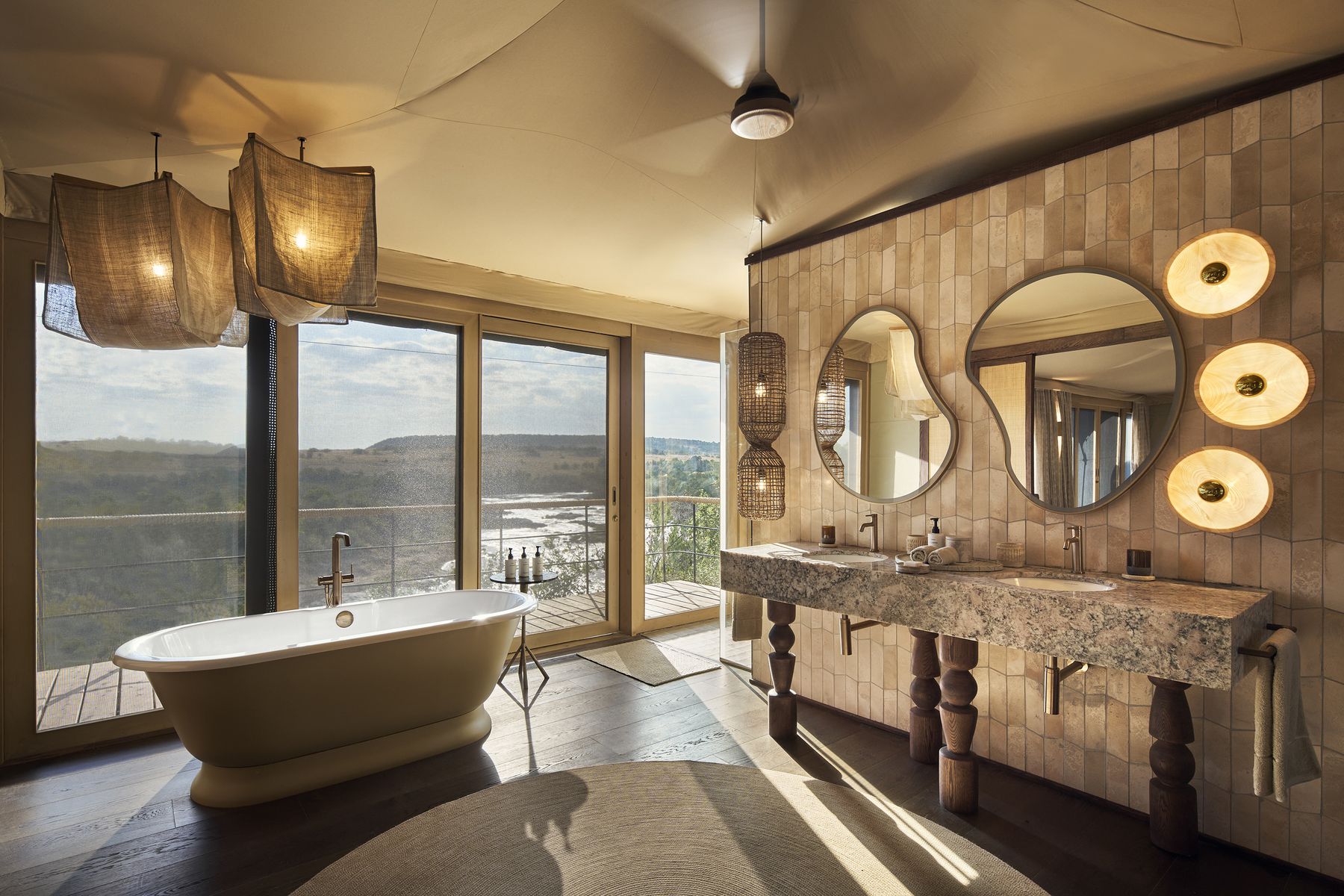 Bathroom in a Kinara suite with a freestanding bath and twin basins beside tall windows over the river