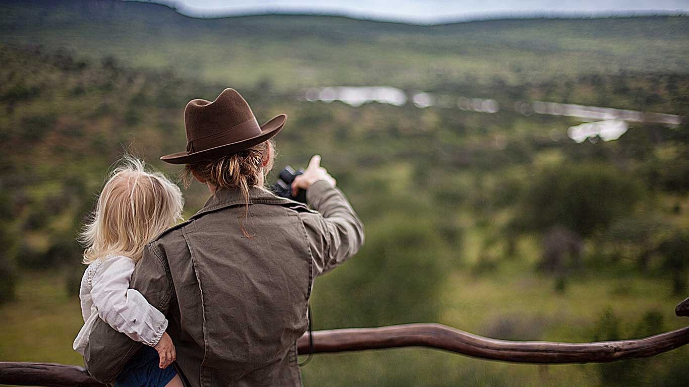 Father and child looking out from the deck at Loisaba Star Beds over bush and a winding river