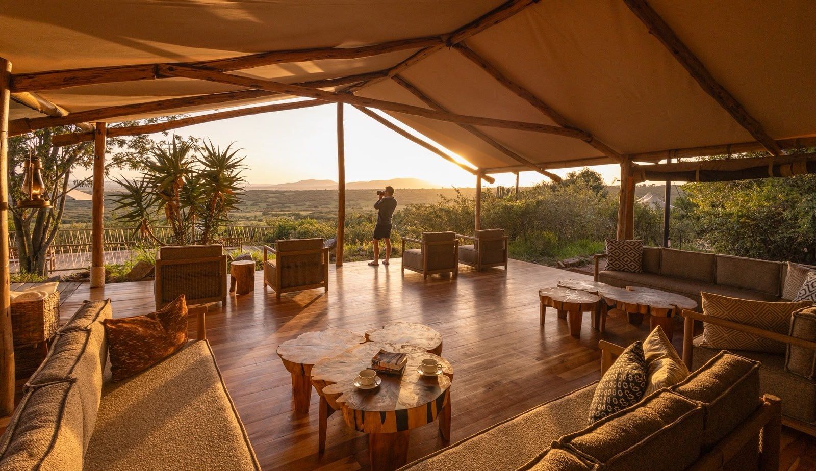 The main lounge deck at Mara Bushtops with sofas and low tables, open to the view at sunset